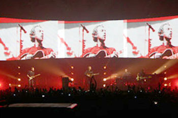 stage in hues of red  with overhead screens of the band during Coldplay's Twisted Logic World Tour, United Kingdom
