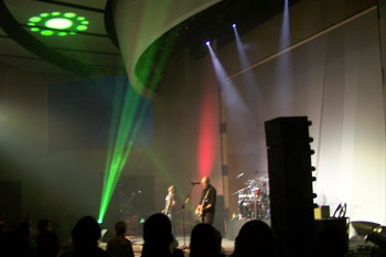 green circle with smaller circles around it gobo on ceiling in front of stage, red wash on side of stage and beams of green light, white beams of light above Tree63 bandmembers playing on stage - Apopka, Florida USA
