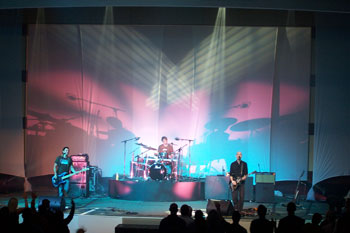 splashes of pinks and aqua colored lights, white beams of light above on the Tree63 bandmembers playing on stage - Apopka, Florida USA