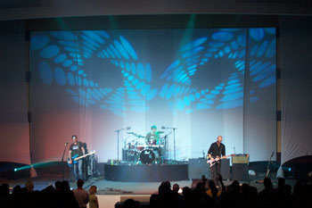 two geometric circle gobo patterns of aqua colored lights side by side, behind Tree63 bandmembers playing on stage - Apopka, Florida USA
