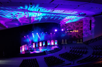 vibrant colors of magenta and blue as beams of light and architectural wash from LED fixtures illuminated above and on the stage, UltraLED DMX Tricolor Bar, SGM Giotto 400 Spot light, SGM G Spot Moving light inside Calvary Orlando building - Winter Park, FL, USA