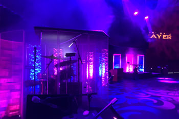 on stage with drum kit with vibrant colors of magenta and blue as beams of light and architectural wash from LED fixtures illuminated above and on the stage, UltraLED DMX Tricolor Bar, SGM Giotto 400 Spot light, SGM G Spot Moving light inside Calvary Orlando building - Winter Park, FL, USA