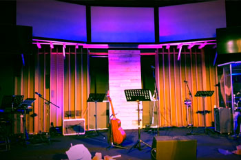 close view of stage with instruments illuminated with vibrant colors of magenta and blue from Techni-Lux UltraLux 7 LED - 6in1 RGBWAUV fixtures inside City View Church - Renton, WA, USA