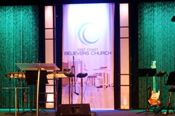 front view of stage with emerald green LED wash on wall at East Coast Believers Church, Casselberry, FL, USA