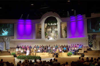 video monitors of the pastor on far side walls, four SGM Ribalta LED RGB color mixing fixtures down lighting wash of magenta on center walls rows of singers on stage, Forestville Baptist Church, Greenville, SC, USA