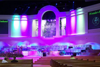 video monitors of the chorus on far side walls, four SGM Ribalta LED RGB color mixing fixtures down lighting wash of blue one center wall and green on other center wall rows of singers on stage, Forestville Baptist Church, Greenville, SC, USA