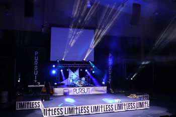 empty stage with band instruments and beams and geometric gobo patterns in a haze effect, using a Techni-Lux Hazer, with white LED and blue LED fixtures from Techni-Lux UltraLux 7 LED - 6in1 RGBWAUV, Showtec Phantom 75 at the Limitless Youth Conference, Molalla, OR, USA