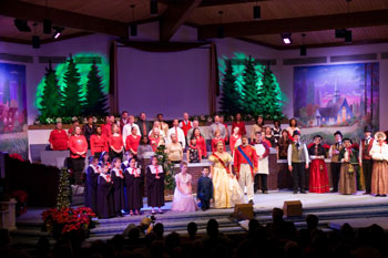  people dressed in Victorian era black and white choir gowns holding red candles, people dressed as royalty and people dressed like  on stage and a  - Journey to the Manger Musical - South Orlando Baptist Church, Orlando, FL, USA