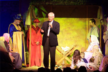 close up of stage with a man speaking to audience, actors as 3 wise men, shepherds, holy                              family with yellow LED with geometric gobo pattern on manger, Southpointe, Leesburg, FL, USA