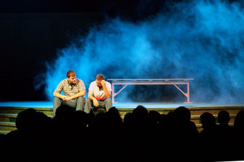 close up scene of two men sitting at the front of the stage talking with an omnious blue haze behind them with a gym bench of Your Final Destination - Victory Church, Lakeland, FL, USA