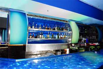 bar with illuminated blue panels and behind the alchol bottles on shelves with a water relecting light bar counter, Aqua Lounge, Daytona Beach, Florida