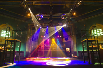 dance platforms on each side on dance floor, corner walls have video 16 monitor with abstract white and black imagery, mirror balls, beams of light in vibrant hues of white, purple, blue and vibrant beams of white, yellow and purple lights with gobo geometric patterns on dance floor inside  Tabu - Orlando, Florida, USA