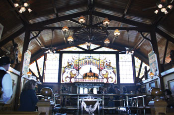 large window panals with floral arabesque stainglass in hues of earthtones of browns with green, red and aqua accent colors in floral pattern above bar says Cheyenne Saloon & Opera House with silhoette of cowboys on horses inside Cheyenne Saloon - Orlando, Florida, USA