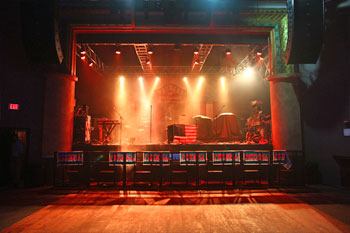 large speakers on each side of stage with band instruments and props illuminated with beams of white LEDs fromSGM Idea Moving LED 100 fixtures, red LED from Techni-Lux UltraLED FlexiPar LED TriColor RGB fixtures The Beacham - Orlando, Florida, USA