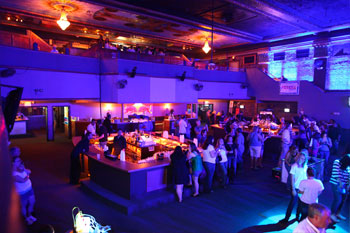 people ordering at the bar with upper mezzanine dining area in the background hues of blues and purples illuminate the theatre at The Beacham - Orlando, Florida, USA