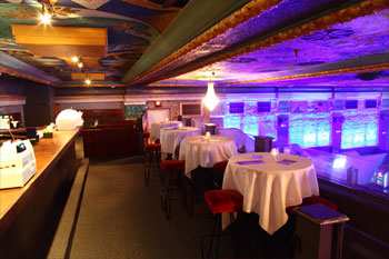 upper mezzanine dining area covered tables LED candles on top and bench chairs counter to order food with a view of the floor walls of theatre vibrant blues insideThe Beacham - Orlando, Florida, USA