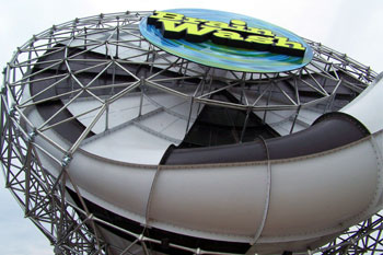 underneath the funneled part of the Brainwash Water Slide which has black and white with geometric triangular metal patterns with the sign yellow and black letters saying brainwash mounted on a round plate with swirls of blue, aqua and green background, Wet 'n Wild - Orlando, Florida, USA