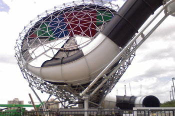 under construction showing a cut away of blue, red, green round interior walls and the exterior black and white checkered pattern with geometric triangular metal patterns around the funnel portion of Brainwash Water Slide, Wet 'n Wild - Orlando, Florida, USA