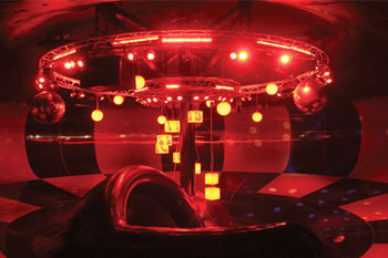 illuminated red interior mounted on top near ceiling a large outer round truss are Pulsar ChromaScape SS fixtures, Pulsar ChromaStrip fixtures, big mirror balls reflecting colorful circles on multicolored walls  red illumined Pulsar ChromaSpheres, 8 red illuminated Pulsar ChromaCubes with groovy numbers in red and green hanging from a smaller round truss, just below large truss, Disco H2O Water Slide, Wet 'n Wild - Orlando, Florida, USA