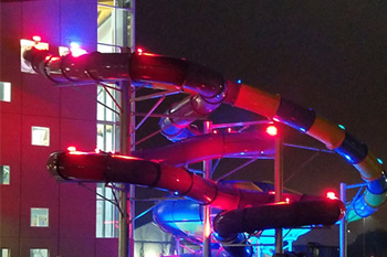 exterior section of water slide connected to interior of building and illuminated wtih vibrant red led lights at Parrot Cove Indoor Water Park, Garden City, Kansas, USA