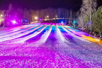 vibrant colors of pink, purple, yellow royal blue and aqua green from LED fixutres illuminating the snow at Lunar Lights Tubing Peek 'n Peak Resort - Clymer, New York U.S.A.