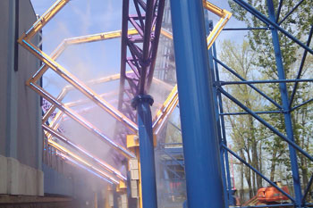 misty fog and blue rollercoaster tracks going through yellow diamond shaped metal structures with mounted lit LED Pulsar Chromastrip fixtures with vibrant blue and red colors on the Bizarro Coaster Thrill Ride, Six Flags New England - Agawam, Massachusetts, USA