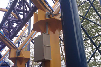 blue rollercoaster tracks going through yellow diamond shaped metal structures with mounted lit LED Pulsar Chromastrip fixtures with vibrant blue color and  gray juncture box mounted at the base of it on the Bizarro Coaster Thrill Ride at night, Six Flags New England - Agawam, Massachusetts, USA