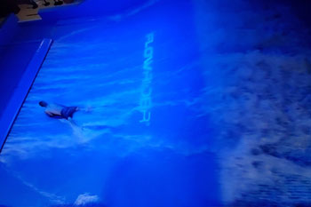 person surfing on illuminated water wave in vibrant hue of blue on the FlowRider Surf Machine, Splash Lagoon Indoor Water Park, Erie, Pennsylvania, USA