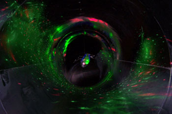 BLISS Light Custom Laser Unit  vibrant colors of green and red particles reflecting like a spiral along the the dark black walls of the water tube interior of the Black Hole Water Slide, Wet 'n Wild - Orlando, Florida, USA