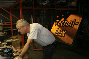 Techni-Lux in-house lighting designer Tony Hansen programming large road sign that reads join Techni-Lux with American flag the villianJustice League: Alien Invasion Warner Bros. Movie World - Gold Coast, Australia