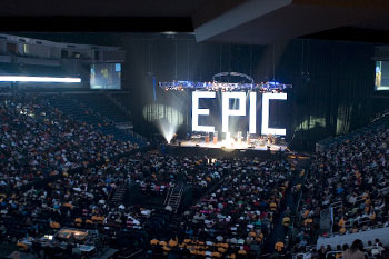 arena full of people with the stage off in the distance with a huge backdrop of intensly bright LED lit individual letters that spell out the word EPIC at the Victory World Church Epic Easter Production - Duluth, Georgia