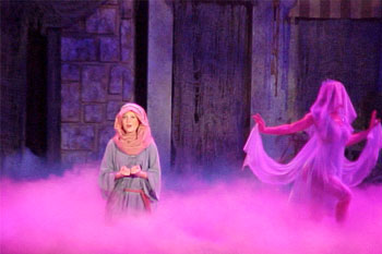 magenta colored fog with a performer singing with shepard costume and some ghostly woman walking off town building prop set, Gabriel's Christmas Story, Calvary Orlando, Winter Park, Florida, USA